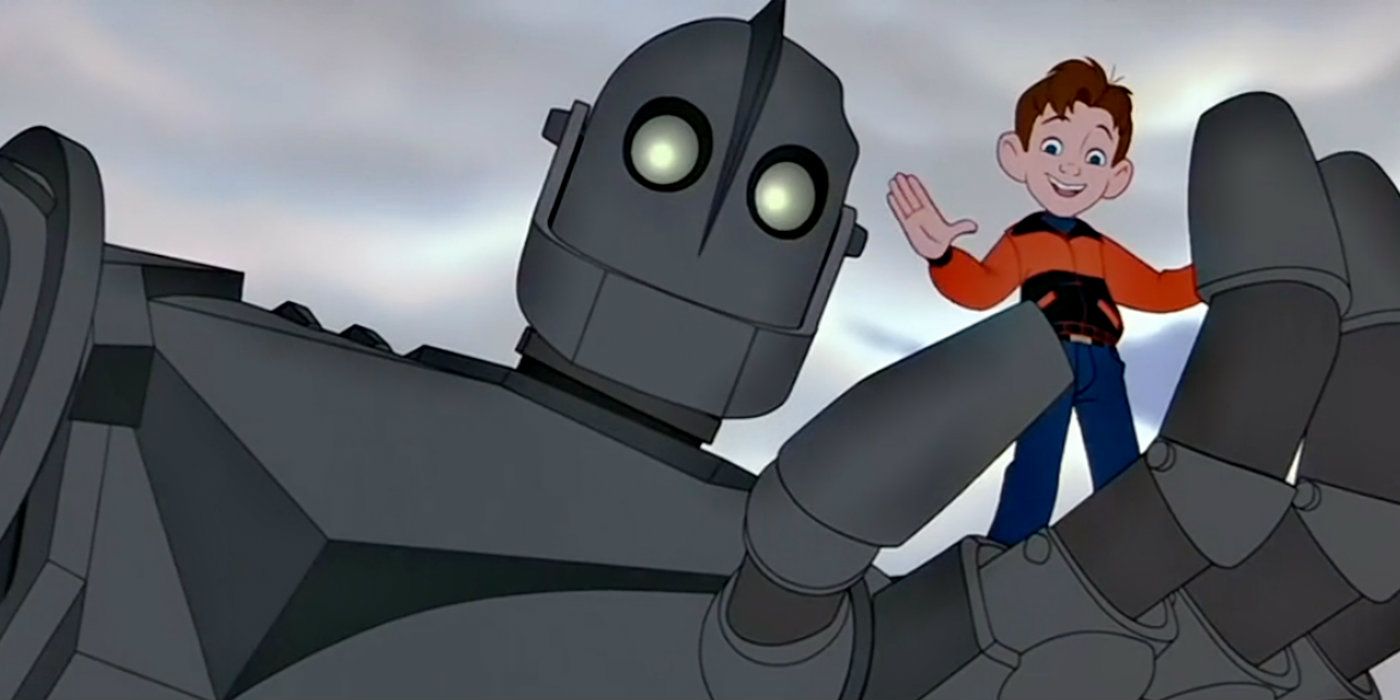 Un baietel face cu mana in timp ce este tinut de un robot urias de la The Iron Giant